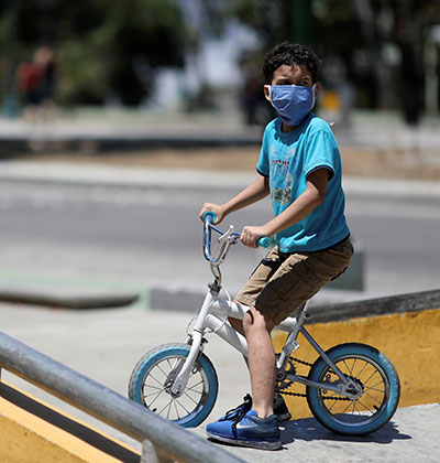 ילד עם מסכה רוכב לבד על האופניים בימי קורונה / צילום: Manaure Quintero, רויטרס