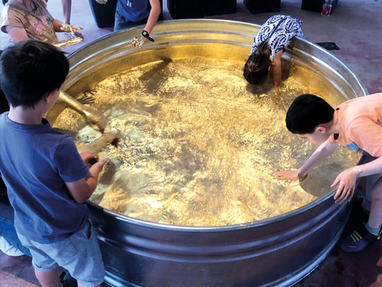 המוזיאון הנייד זומו בחצור הגלילית. ילדים טובלים בבריכת זהב שיצרה כבסה בהשראת חוני המעגל 