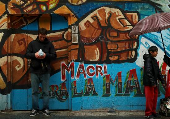 אדם עומד השבוע ליד גרפיטי שקורא לנשיא ארגנטינה מאוריסיו מאקרי להתפטר / צילום: רויטרס
