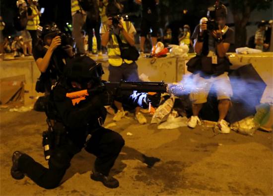 שוטר יורה גז מדמיע על מפגינים מחוץ לבית המחוקקים בהונג קונג / צילום: Tyrone Siu, רויטרס