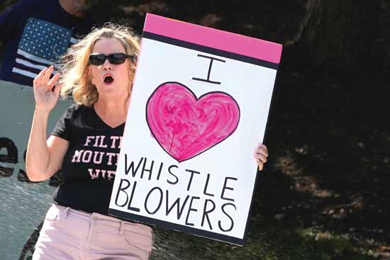 "אני אוהבת מלשינים". מפגינה מחזיקה שלט מול מועדון הגולף שבו משחק טראמפ/ צילום:רויטרס