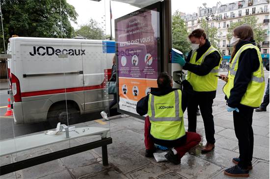 עובדי חברת פרסום החוצות JCDecaux מתקינים מכשיר לחיטוי ידיים בתחנת אוטובוס בפריז / צילום: BENOIT TESSIER, רויטרס