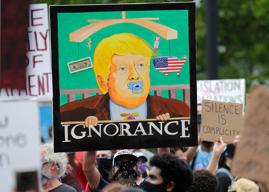 איור של טראמפ עם הכיתוב "בורות" בהפגנה במיאמי, ביום שבת / צילום: Lynne Sladky, Associated Press