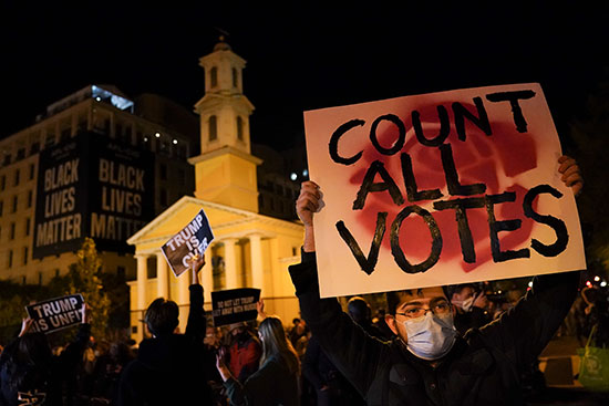 מפגינים נושאים שלטים בליל הבחירות בוושינגטון / צילום: John Minchillo, Associated Press
