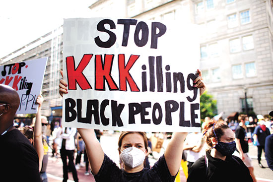 אחת המפגינות מחזיקה בשלט שקורא נגד גזענות ונגד רצח שחורים / צילום: shutterstock, שאטרסטוק
