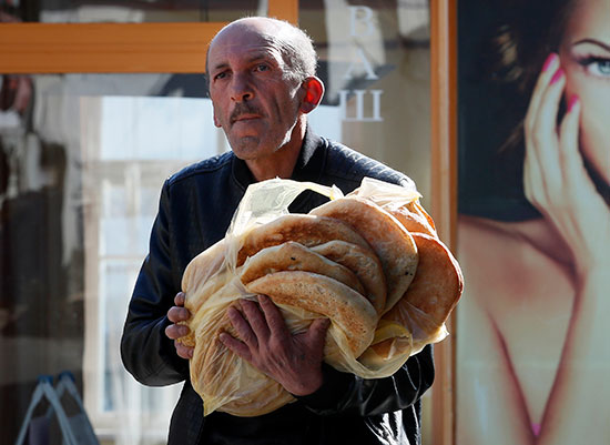 מוכר לחם "לבאש" המסורתי עובר ברחוב ומנסה להמשיך למכור לחם טרי למרות המצב הקשה / צילום: Associated Press