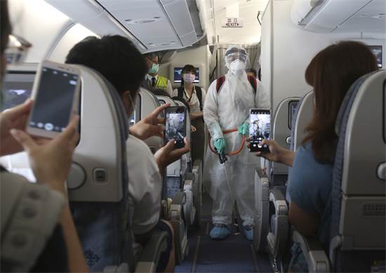 משתתפים בטיסת ה"כאילו" בטיוואן מקבלים הדגמה לאיך עושים חיטוי במטוס / צילום: Chiang Ying-ying, AP