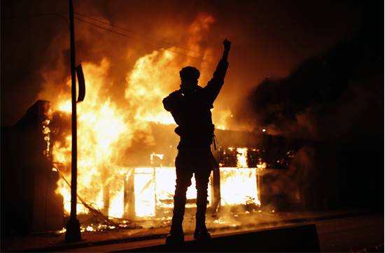 מפגין מול בית עסק להחלפת צ'קים שעולה באש ביום שישי במיניאפוליס, העיר שבה נרצח ג'ורג' פלויד בן ה-46  / צילום: John Minchillo, AP