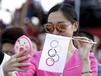 אישה סינית עושה סלפי עם דגל של הטבעות האולימפיות / צלם: רויטרס