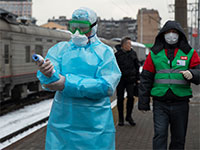 מאבטחים בשדה התעופה במוסקבה מקבלים את בואם של הנוחתים מבייג'ינג עם חליפות מגן בדרך לבדוק טמפרטורות גוף תקינות / צילום: Mark Schiefelbein, Associated Press