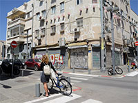 צעירה עם אופניים משקיפה על הרחוב הריק, דרום תל אביב. מאז התפשטות הקורונה משרד הבריאות הורה על סגירת מרבית העסקים במדינה / צילום: איל יצהר, גלובס