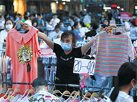סוחר בדוכני הבגדים בווהאן / צילום: Mark Schiefelbein, Associated Press