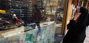 תושבת טהראן בודקת שער מט"ח אצל חלפן מקומי / צילום: רויטרס