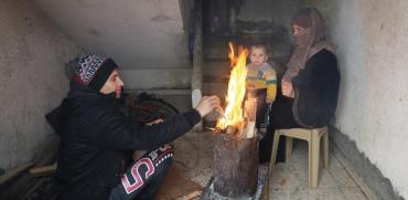 משפחה עזתית מתחממת / צילום: רויטרס, Ibraheem Abu Mustafa