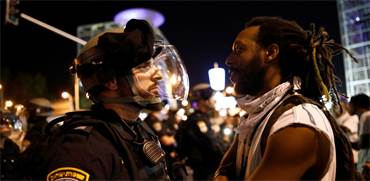 מפגין ושוטר במחאה על אלימות משטרתית / צילום: Corinna Kern, רויטרס