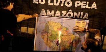 מפגין בסאן פאולו שורף את המפה של יבשת אמריקה בעקבות אדישותו של נשיא ברזיל לשריפות ביערות הגשם / צילום: רויטרס