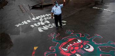 שוטר עומד בכביש שעליו מצויר ציור המעורר מודעות לנגיף הקורונה / צילום: Anupam Nath, AP