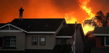אדם על גג ביתו בקליפורניה בשבוע שעבר / צילום: Jae C. Hong, Associated Press