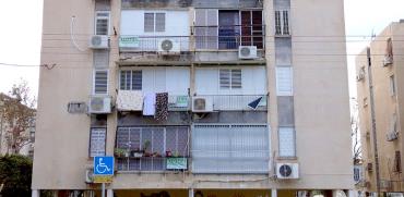שלטים "חתמנו" תלויים על חלונות של אחד הבניינים בשכונת יפו ד' / צילום: גיא נרדי