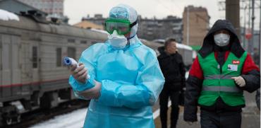 מאבטחים בשדה התעופה במוסקבה מקבלים את בואם של הנוחתים מבייג'ינג עם חליפות מגן בדרך לבדוק טמפרטורות גוף תקינות / צילום: Mark Schiefelbein, Associated Press