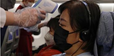 מדידת חום לנוסעת על טיסה יוצאת מסין  / צילום: Associated Press