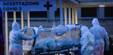 אנשי צוות רפואיים מובילים חולה קורונה לבית חולים ברומא בחליפות מגן / צילום: Associated Press