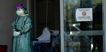 רופאה, מצויידת בחליפת מגן ומסיכה, ממתינה במפתן הדלת, לחולה קורונה הבא שעומד להגיע  / צילום: Alvaro Barrientos, Associated Press