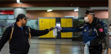 שוטר מחלק מסכות לעוברים בתחנת הרכבת, ספרד / צילום: Bernat Armangue, Associated Press