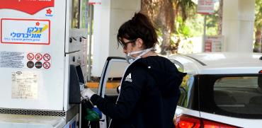 אזרחית ממלאת דלק עם כפפות בצל הקורונה / צילום: איל יצהר, גלובס