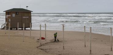עובד עירייה מנקה בחוף של בת ים / צילום: Sebastian Scheiner, Associated Press
