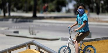 ילד עם מסכה רוכב לבד על האופניים בימי קורונה / צילום: Manaure Quintero, רויטרס