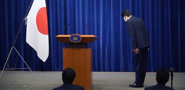 ראש ממשלת יפן, שינזו אבה, קד קידה לדגל יפן לפני תחילת מסיבת העיתונאים, שבה הודיע על פרישתו ביום שישי / צילום: Franck Robichon, Associated Press
