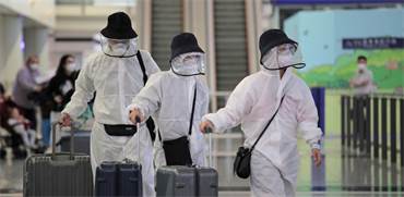 נוסעים לובשים מיגון מפני נגיף הקורונה בשדה התעופה בהונג קונג / צילום: Kin Cheung, AP