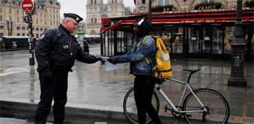 שוטר צרפתי בודק את מסמכיו של אדם שיצא מביתו בפריז / צילום: Francois Mori, AP