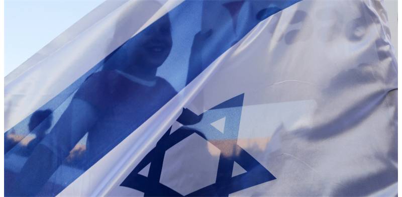 ילדה נראית מבעד לדגל ישראל / צילום: רויטרס