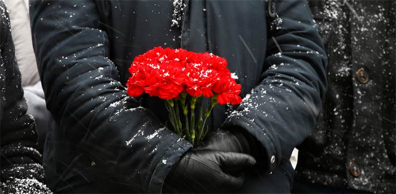 אישה מחזיקה פרחים בעצרת לזכרון השואה בגרמניה / REUTERS/Vasily Fedosenko