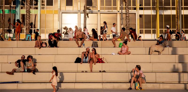 אנשים יושבים בטיילת בתל אביב ליד חוף הים בזמן גל חום / צילום: Oded Balilty, AP