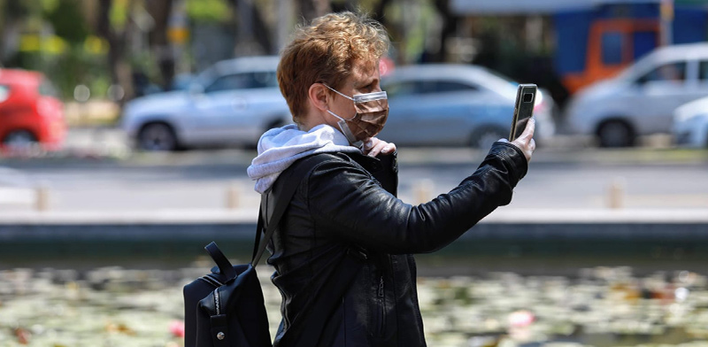 צעיר עם מסיכה וטלפון נייד בתל אביב, בעקבות התפשטות נגיף הקורונה / צילום: שלומי יוסף, גלובס