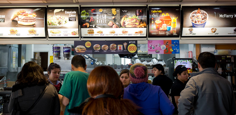 עומדים בתור לקניית מזון מהיר מול המסכים הצבעוניים עליהם מרצד התפריט / צילום: Esteban Felix, Associated Press