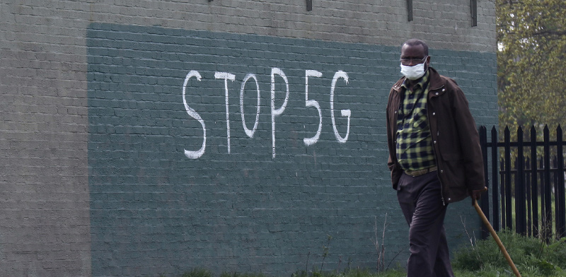 אדם עם מסכה בלונדון, על רקע גרפיטי נגד רשתות 5G  / צילום: RUSSELL BOYCE, רויטרס
