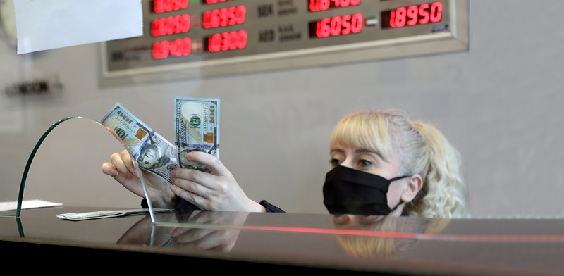 עובדת דלפק בדוכן להמרות מטבע ממירה לשטרות דולרים / צילום: Burhan Ozbilici, Associated Press