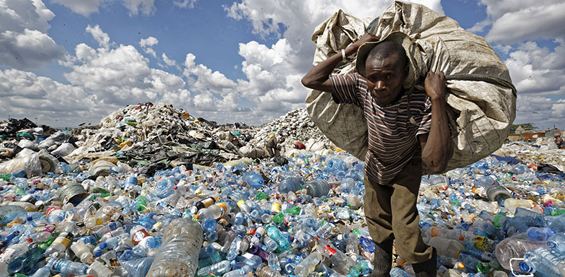 אזרח קניה נושא שק של פלסטיק למחזור בשכונת העוני דנדורה בניירובי  / צילום: Ben Curtis, Associated Press