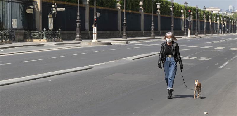 הקורונה בצרפת: אישה עם מסכת הגנה מטיילת עם כלבה בפריס השוממת / צילום: AP