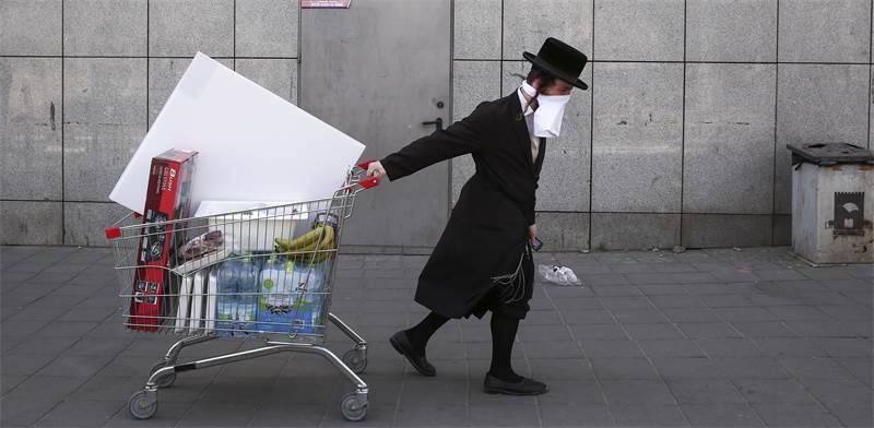 חרדי תושב בני ברק עם מסכת פנים סוחב עגלת קניות  / צילום: Oded Balilty, AP