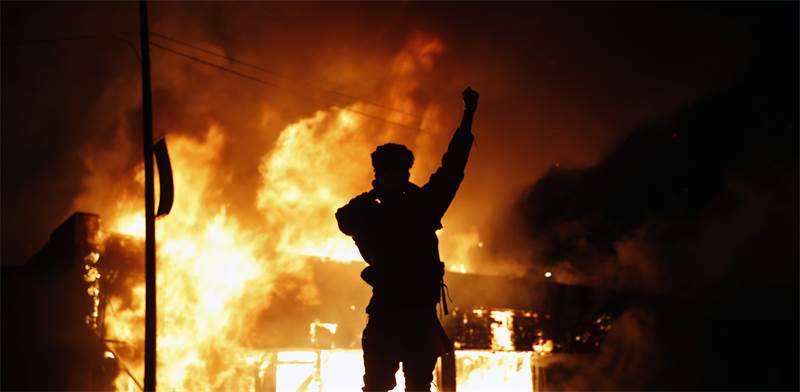 מפגין מול בית עסק להחלפת צ'קים שעולה באש ביום שישי במיניאפוליס, העיר שבה נרצח ג'ורג' פלויד בן ה-46  / צילום: John Minchillo, AP